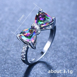 Silver bow ring featuring colorful mystic topaz and micro-pave stones on dark blue background