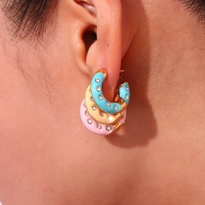 Macro shot of 18K gold-plated C-shaped enamel earrings with sparkling rhinestones