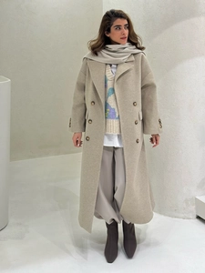 Detail of light beige double-breasted wool coat with peaked lapels and side flap pockets