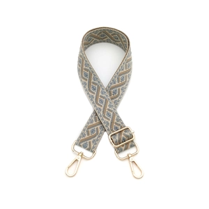 Détail d'une bandoulière tissée à motifs géométriques avec des mousquetons dorés chic