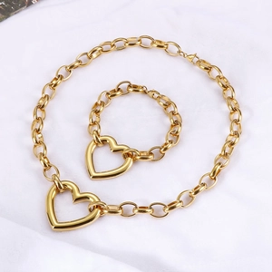Macro view of gold chunky chain necklace and bracelet set with large heart pendants