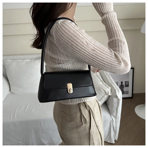 Side view of model wearing a black French baguette bag with gold buckle hardware