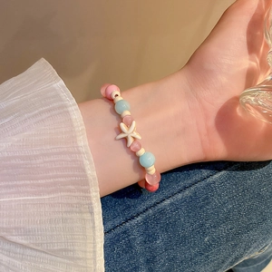 Close-up of a sweet ocean-style beaded bracelet with a white starfish charm on a wrist