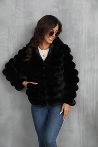 Detail showing the plush texture of a black faux fur hooded jacket and denim jeans style