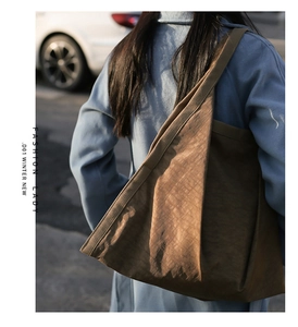 Street style view of a brown tote bag with wrinkled texture on a blue coat model