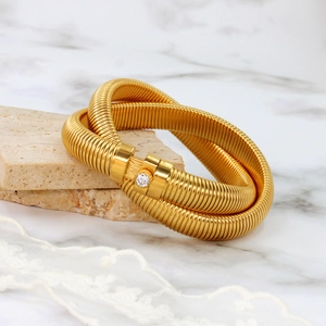 Detail of gold Tubogas spiral bangle with spring texture and sparkling zircon stone