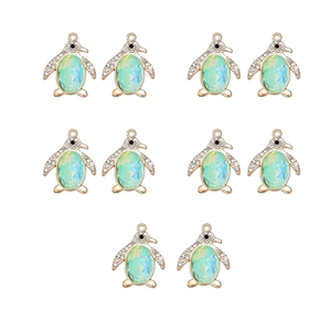 Close-up of 10 gold penguin charms with blue-green opal stones for DIY jewelry making