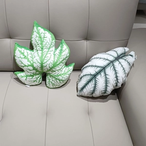 Creative leaf shaped plush pillows featuring monstera and begonia leaf designs on sofa