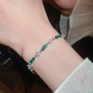 Close-up of sparkling waterdrop silver bracelet with green zircons on a woman wrist