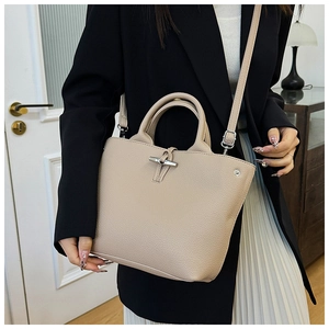 Detail of beige lychee leather tote bag featuring a vintage metal bamboo buckle closure