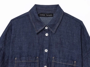 Primo piano dettagliato del colletto della camicia di jeans blu scuro con bottoni metallici