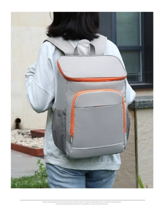 Detail of grey insulated backpack with orange zippers and mesh pockets on model back