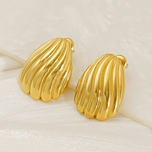 Gros plan de boucles d'oreilles dorées avec texture rainurée sur du tissu en soie