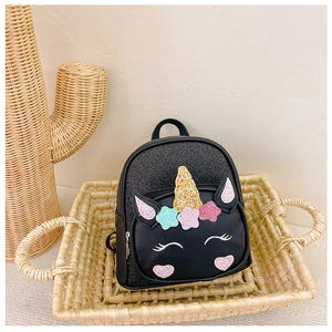 Detail of a black unicorn kids backpack with glitter star patterns in a cozy setting