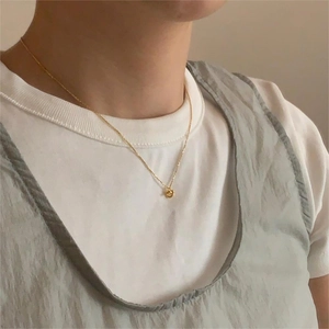 Close-up of a delicate gold-toned knotted heart pendant necklace worn on the collarbone
