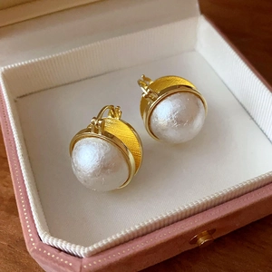 Close-up of elegant gold flower pearl earrings in a pink jewelry display box