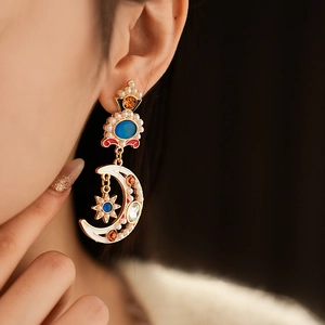 Detailed view of vintage gold moon and star earring with colorful enamel and pearls