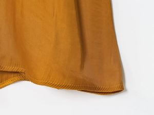 Macro detail of high-quality stitching on the hem of a gold satin midi dress fabric