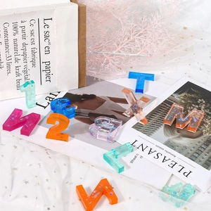 Macro detail of colorful resin alphabet and number charms with sparkling sequins and gold foil