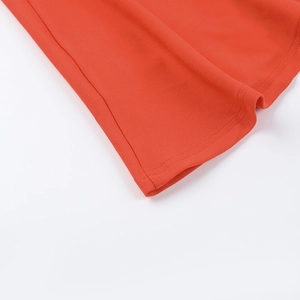 Detail shot of orange dress hem with clean stitching and breathable crepe texture