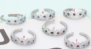 Set of 6 adjustable evil eye rings with colorful zircon inlays on mint background