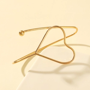 Gros plan d'un bracelet jonc ouvert doré en forme de cœur au fini métallique lisse