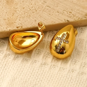 Boucles d'oreilles goutte dorées avec croix en cristal sur fond de pierre élégant