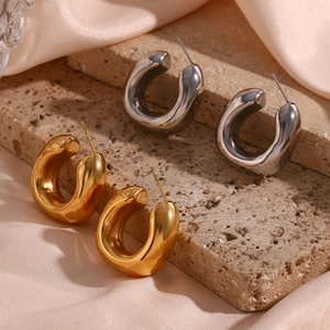 Detail view of square bevel hollow hoop earrings in gold and silver on stone texture