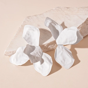 Macro detail of white matte petal earrings showing texture on natural stone surface