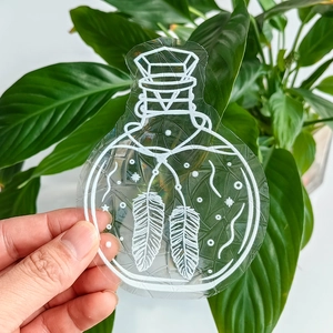 Close-up of a rainbow prism suncatcher window decal featuring feather and star bottle designs