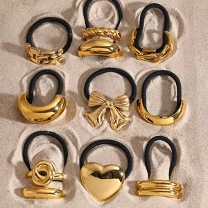 9-piece gold stainless steel hair cuff set with black elastic bands on sand background