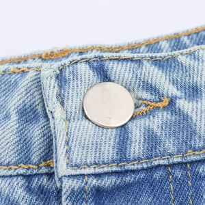 Close-up of high waist denim jeans featuring silver metal button and yellow stitching detail
