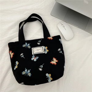 Sac à main en toile noire avec broderie de papillons colorés et motifs floraux blancs
