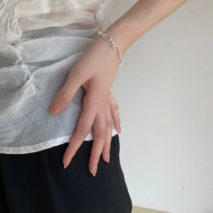 Detail of twisted irregular oval link chain S925 sterling silver bracelet on woman wrist
