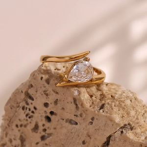 Macro shot of 18K gold-plated wing ring with pear-shaped zircon on textured stone