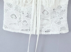 Détail de la texture de dentelle florale blanche et cordon réglable sur la jupe