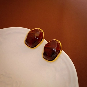 Detailed close-up of vintage resin earrings with gold spiral borders on a white ceramic plate