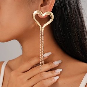 Close-up of heart-shaped gold earrings with sparkling rhinestone tassels on a model