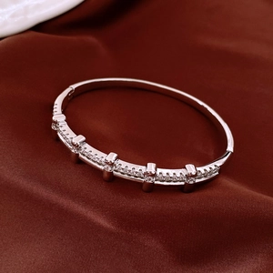 Détail d'un bracelet plaqué argent orné de zircons posé sur un tissu en satin rouge