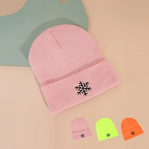 Détail du bonnet en maille rose avec broderie flocon de neige noire et bord replié