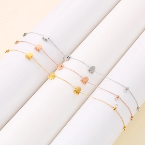Elegant gold and silver tulip pendant bracelets displayed on a white cylindrical stand