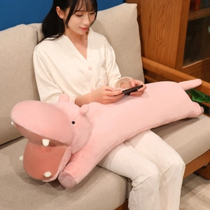 Pink cartoon long hippo plush pillow being held by a woman on a cozy home sofa