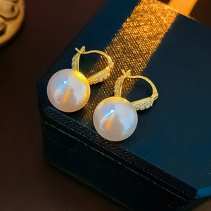 Dettaglio di orecchini di perle placcati in oro con diamanti su una scatola blu