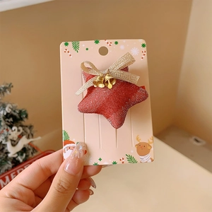 Close-up of a red glitter star hair clip with a golden bow and festive bells for Christmas