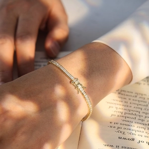 Detail of gold S925 silver tennis chain bracelet with square zircons on a book