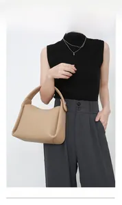 Detail of camel leather handbag with litchi texture and wide strap on model