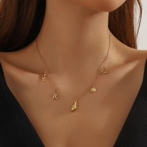 Gold ocean themed necklace with starfish and shell pendants worn by a model