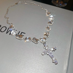 Macro view of crystal cross pendant with shimmering diamonds on silver chain necklace
