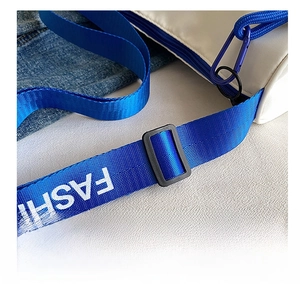 Detail of white bag featuring adjustable blue nylon strap with FASHION text and plastic buckle