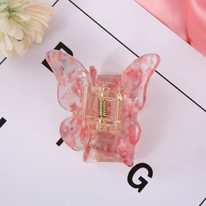 Detail of butterfly-shaped hair clip in pink and white spotted acrylic on display